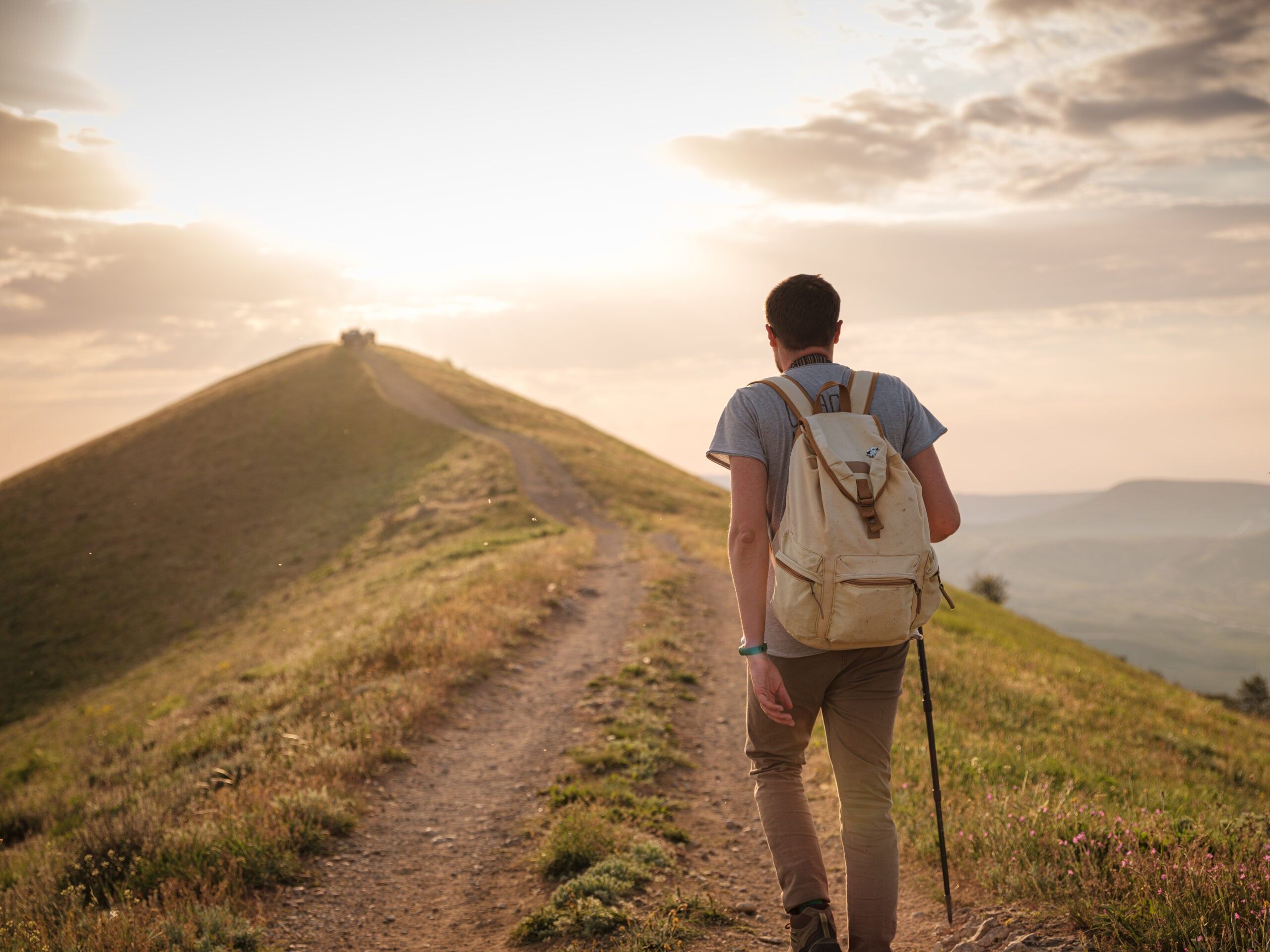 Man walking a trail alone at sunset.