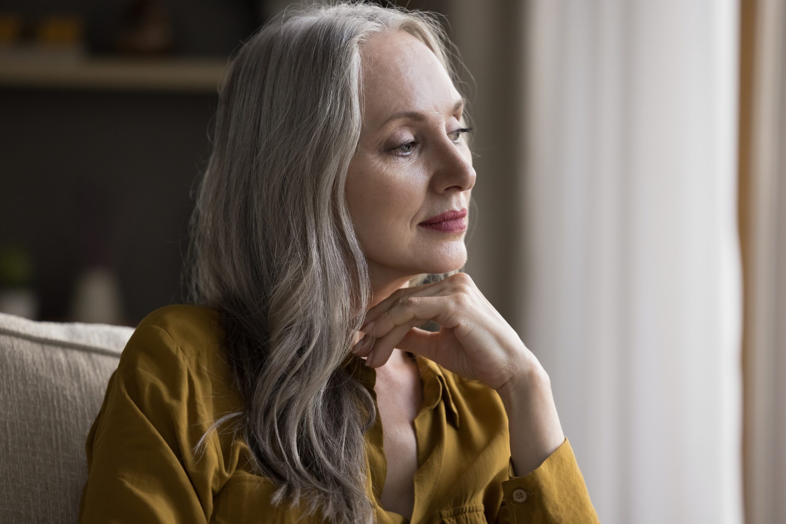 A middle aged woman sitting alone and thinking about her life experiences.