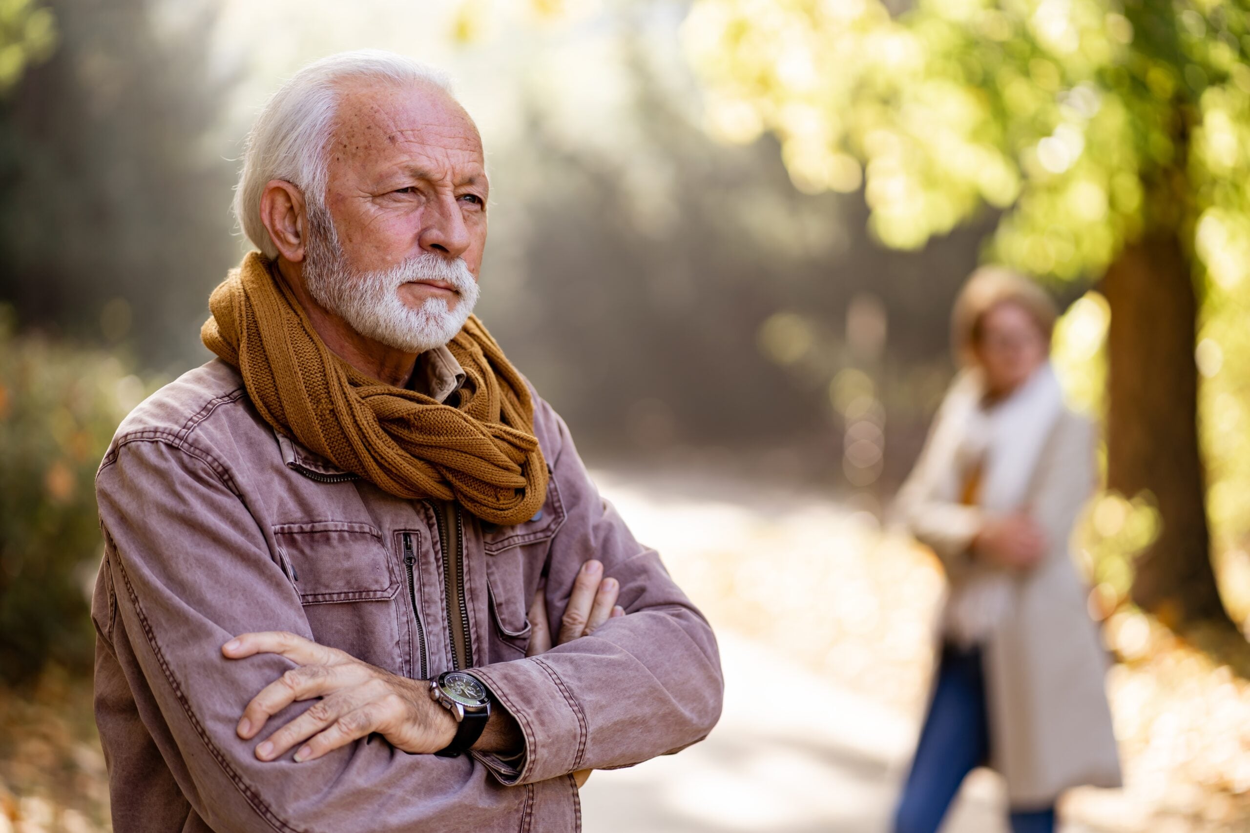 A senior man with his arms crossed looking angry.