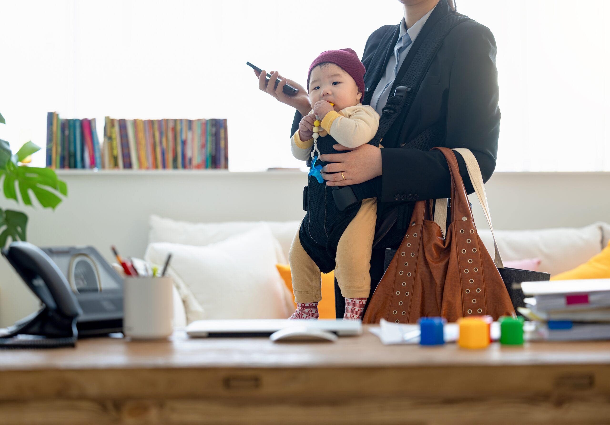 A working mother leaving home to go to the office carrying her baby.