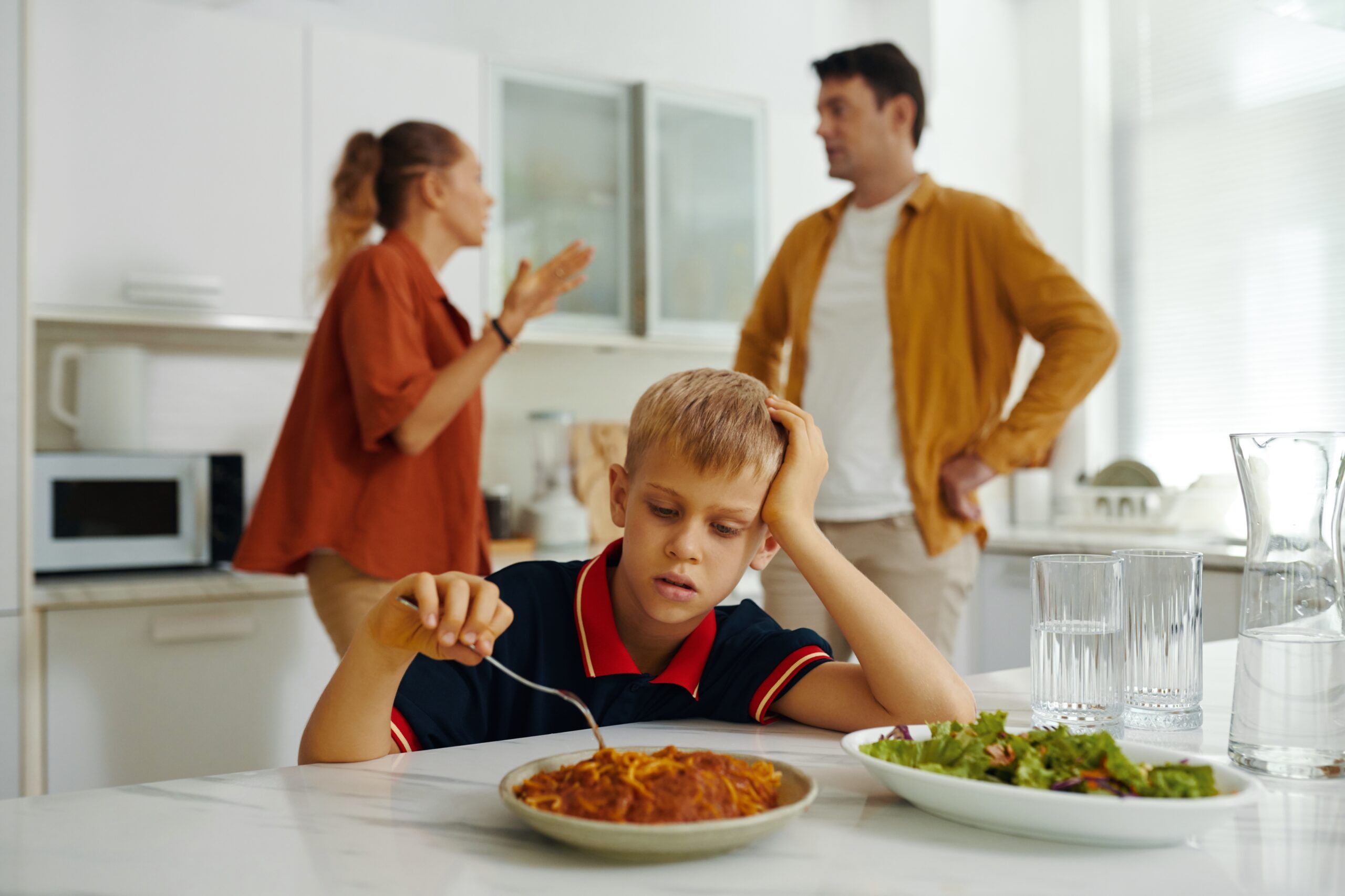 Child eating while parents argue in the background.
