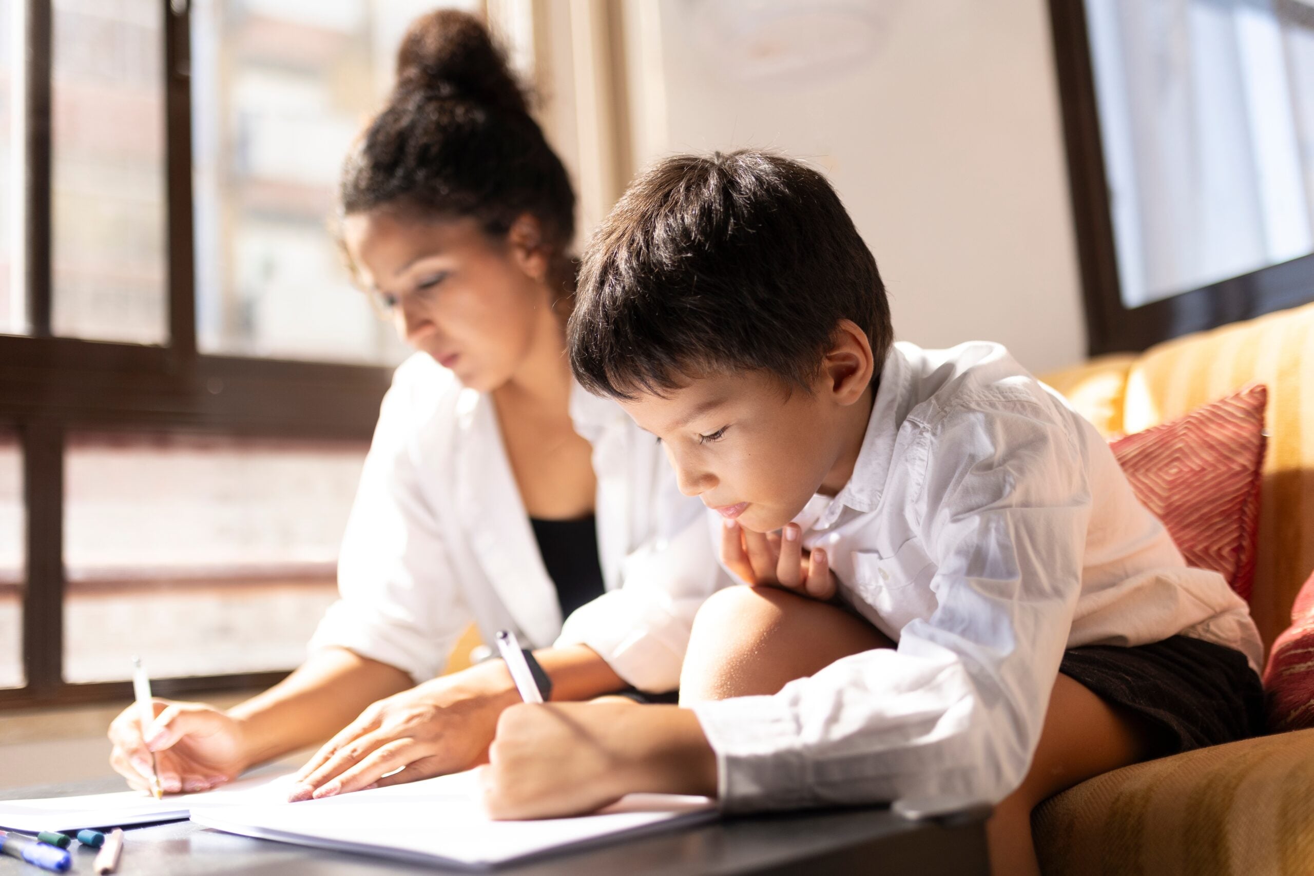 A child doing his homework beside his mother while she works.