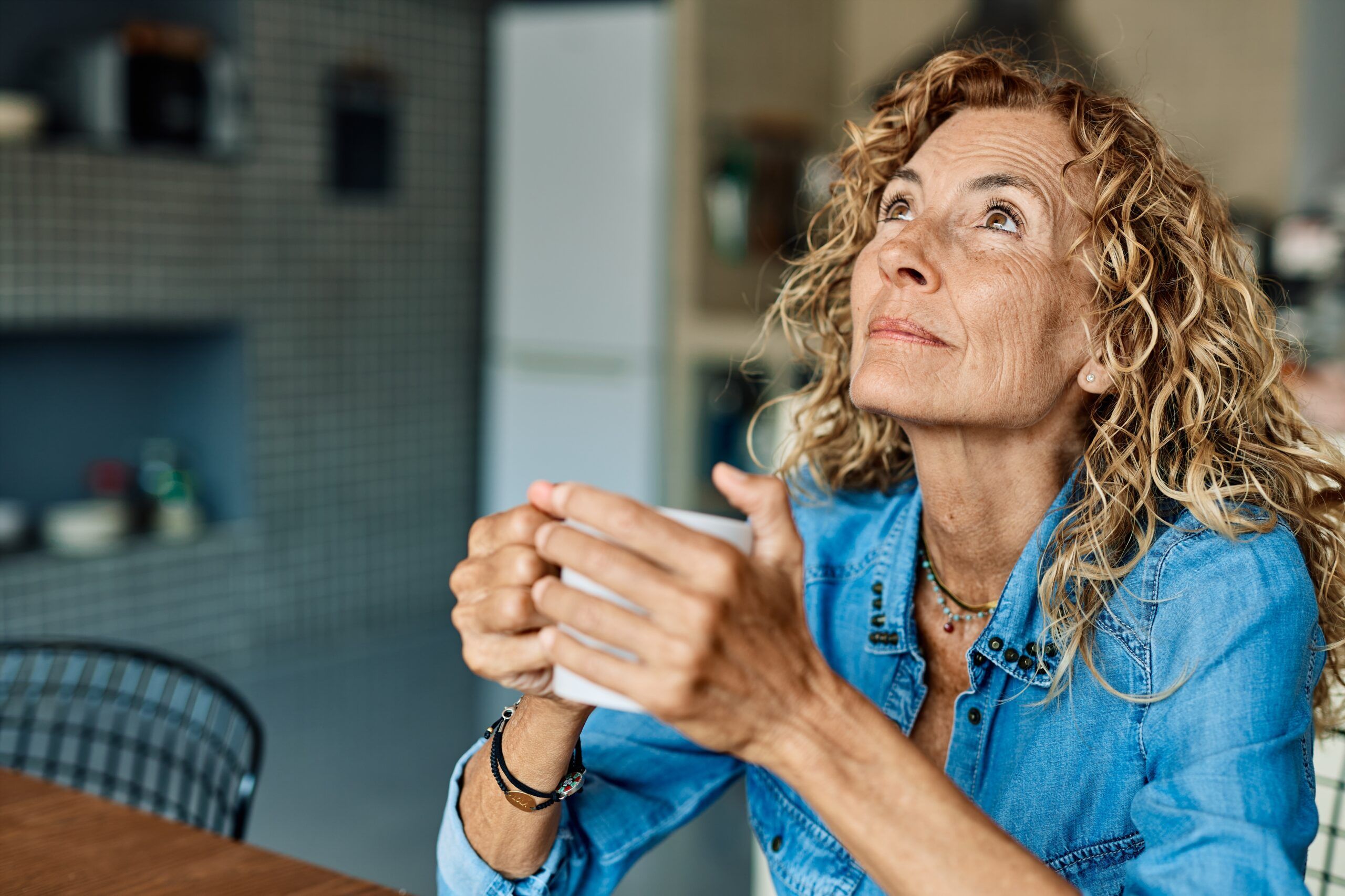 A woman holding a cup of coffee thinking about her life.