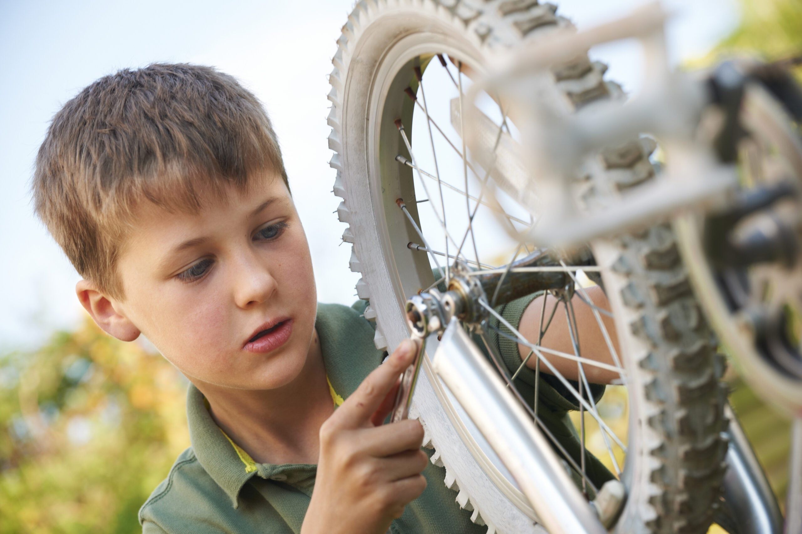 A young boy repairing his own bike.