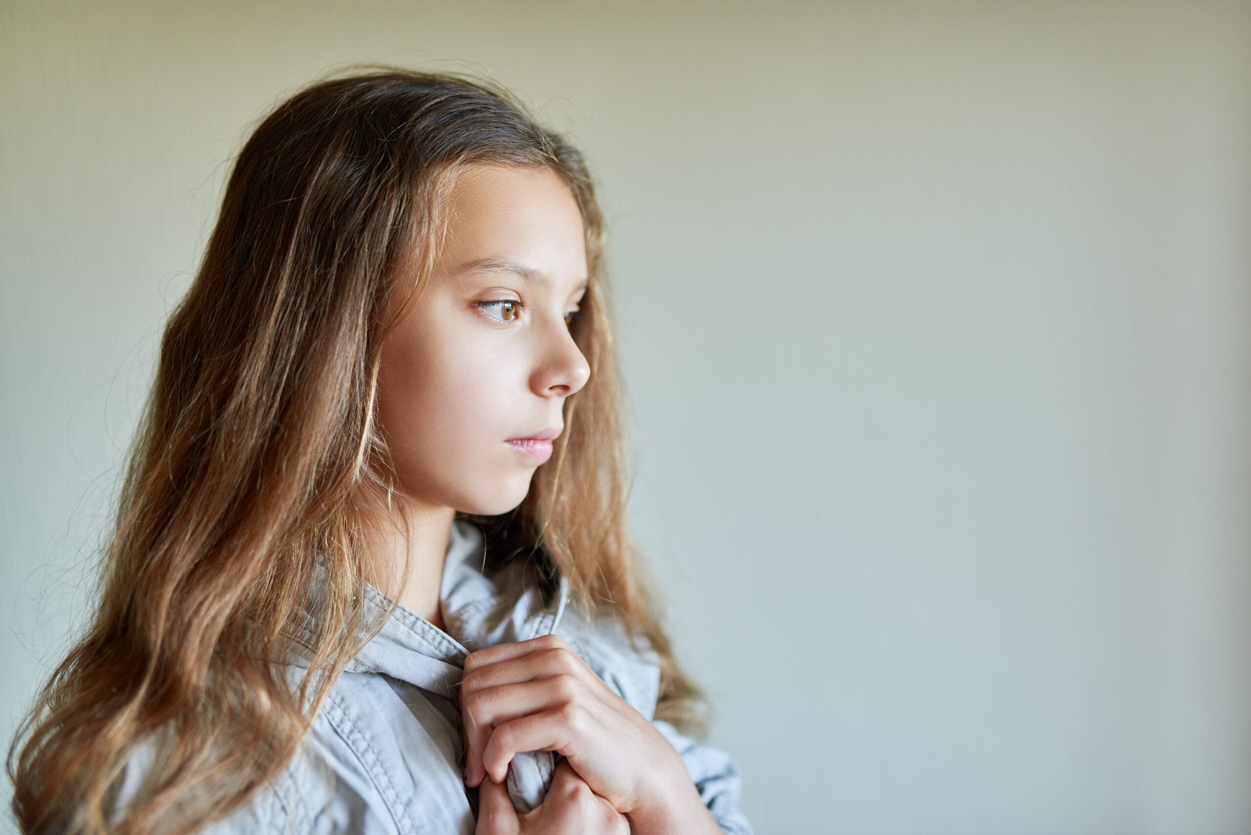 A young child standing alone deep in thought.