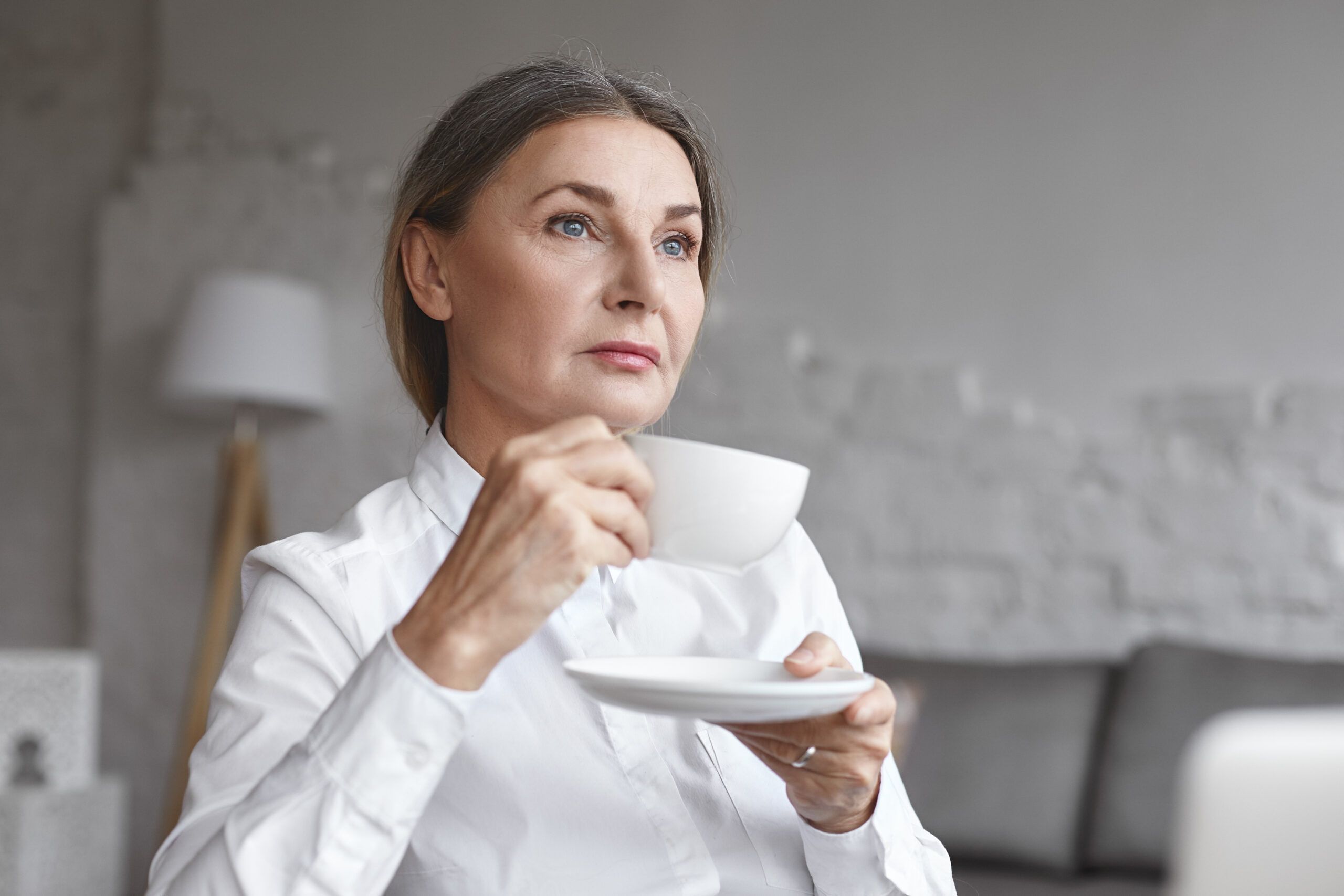 A serious mature woman having coffee alone.