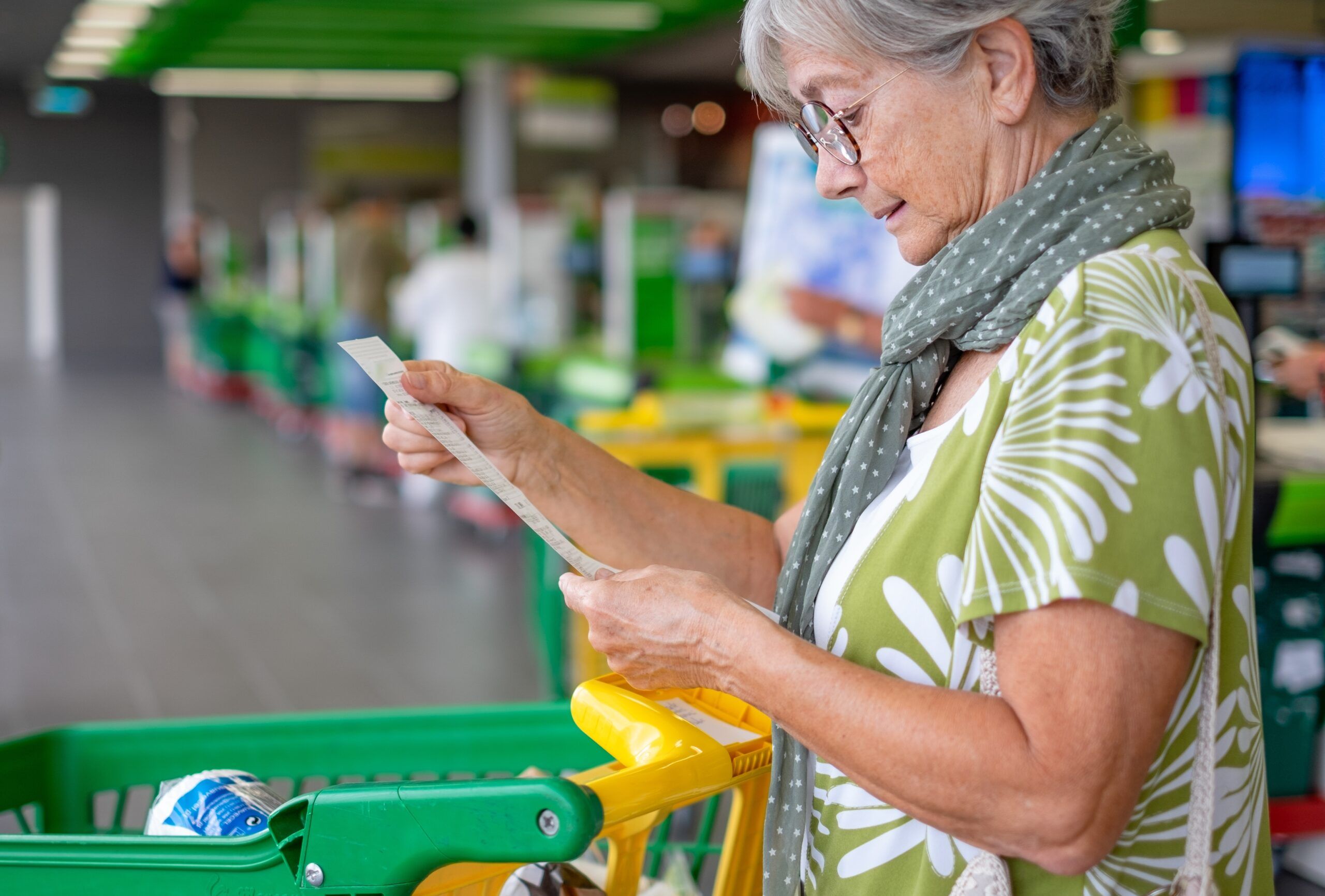 A senior woman looking over her grocery receipt.