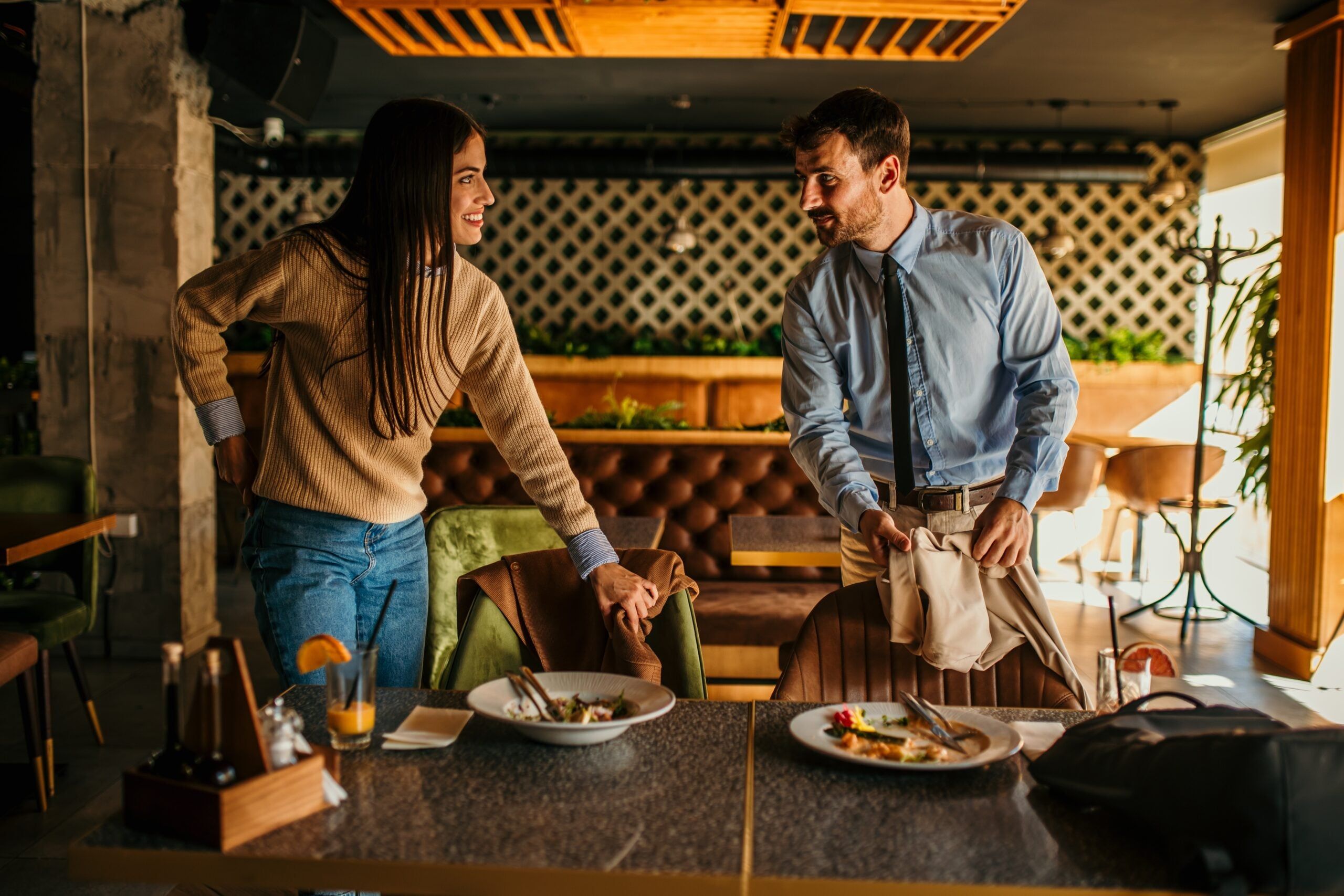 A man and woman tidying their table as they leave a restaurant