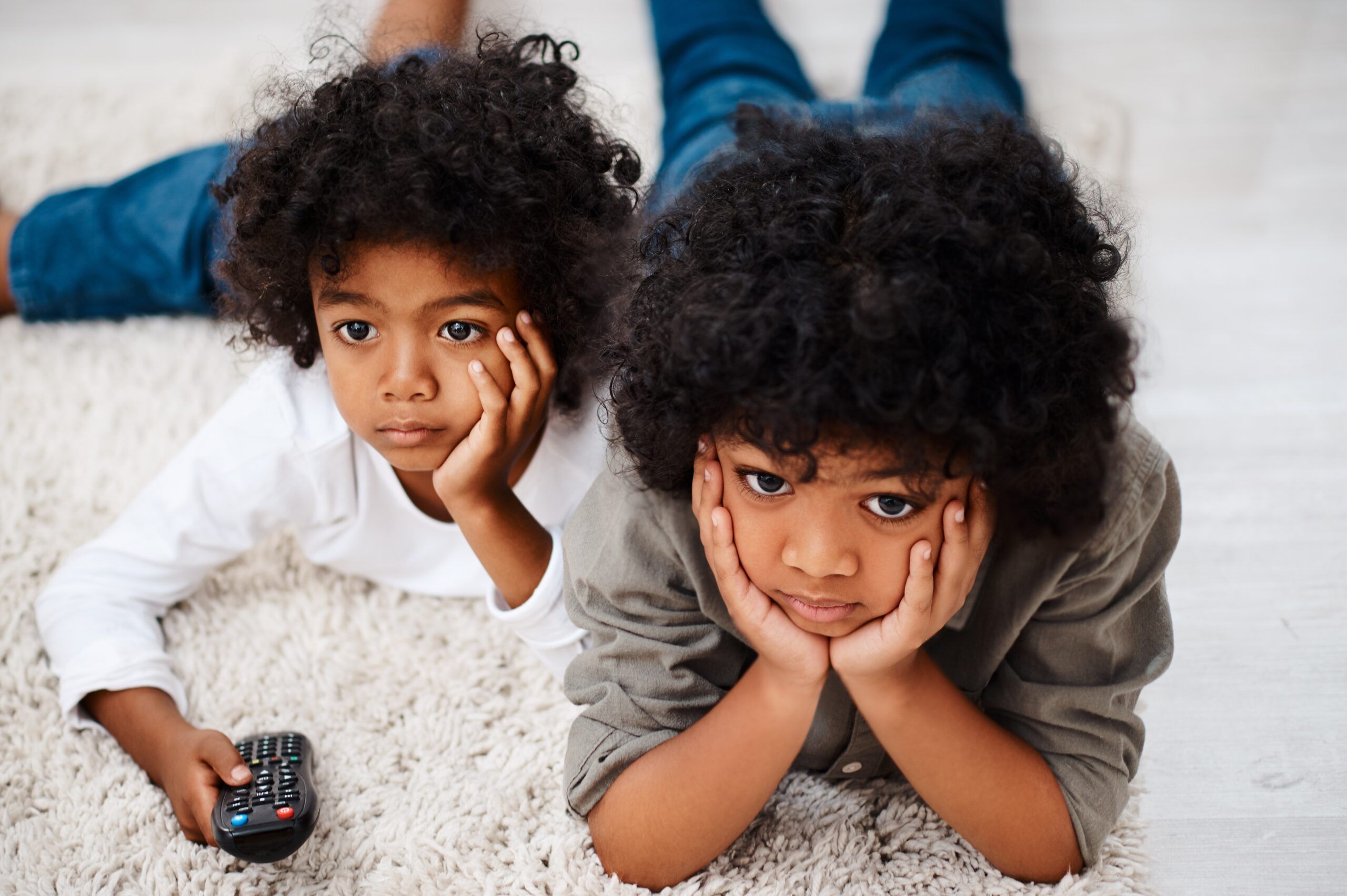 Two young siblings watching TV together.