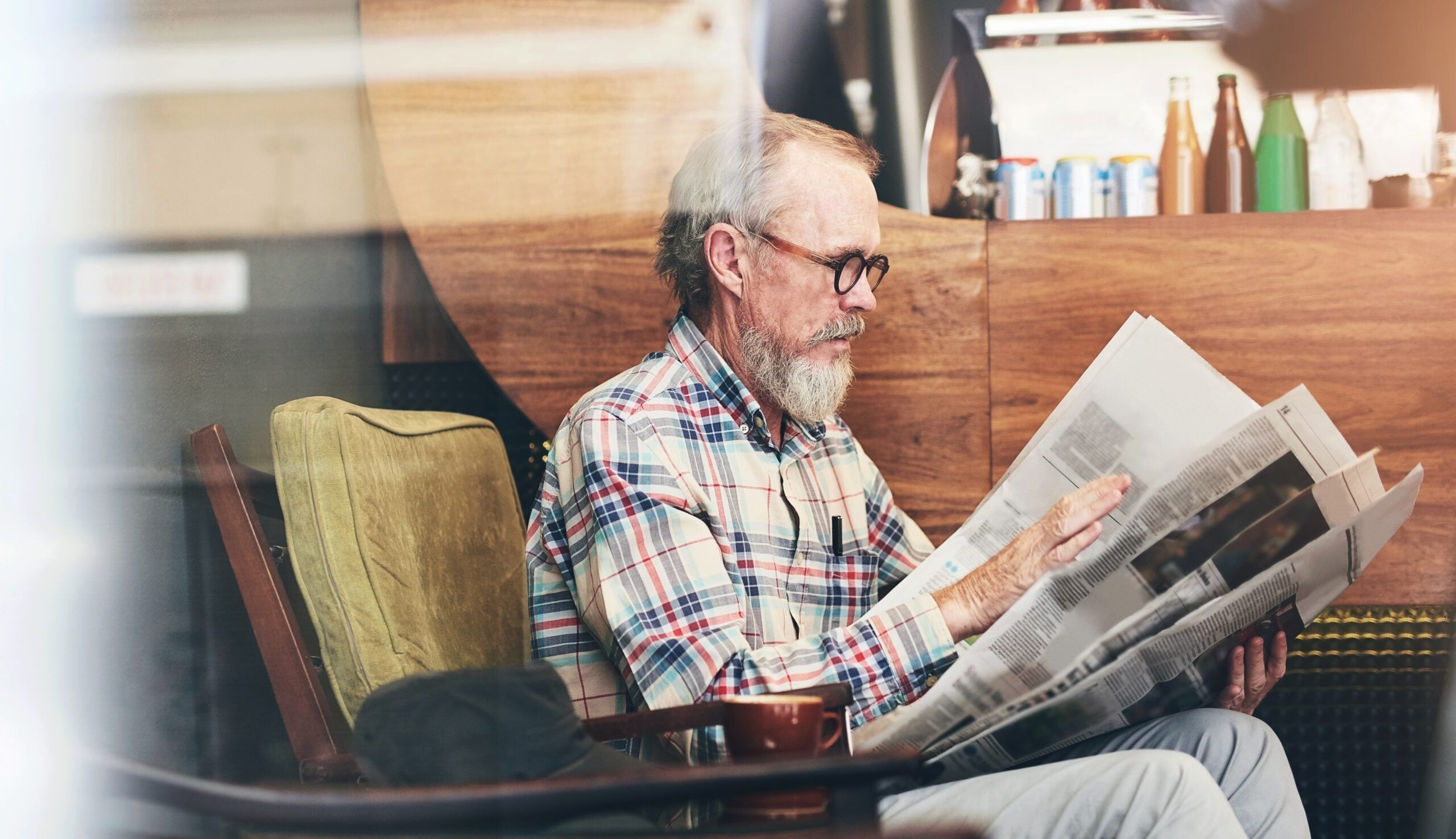A retired senior reading the newspaper at a cafe.