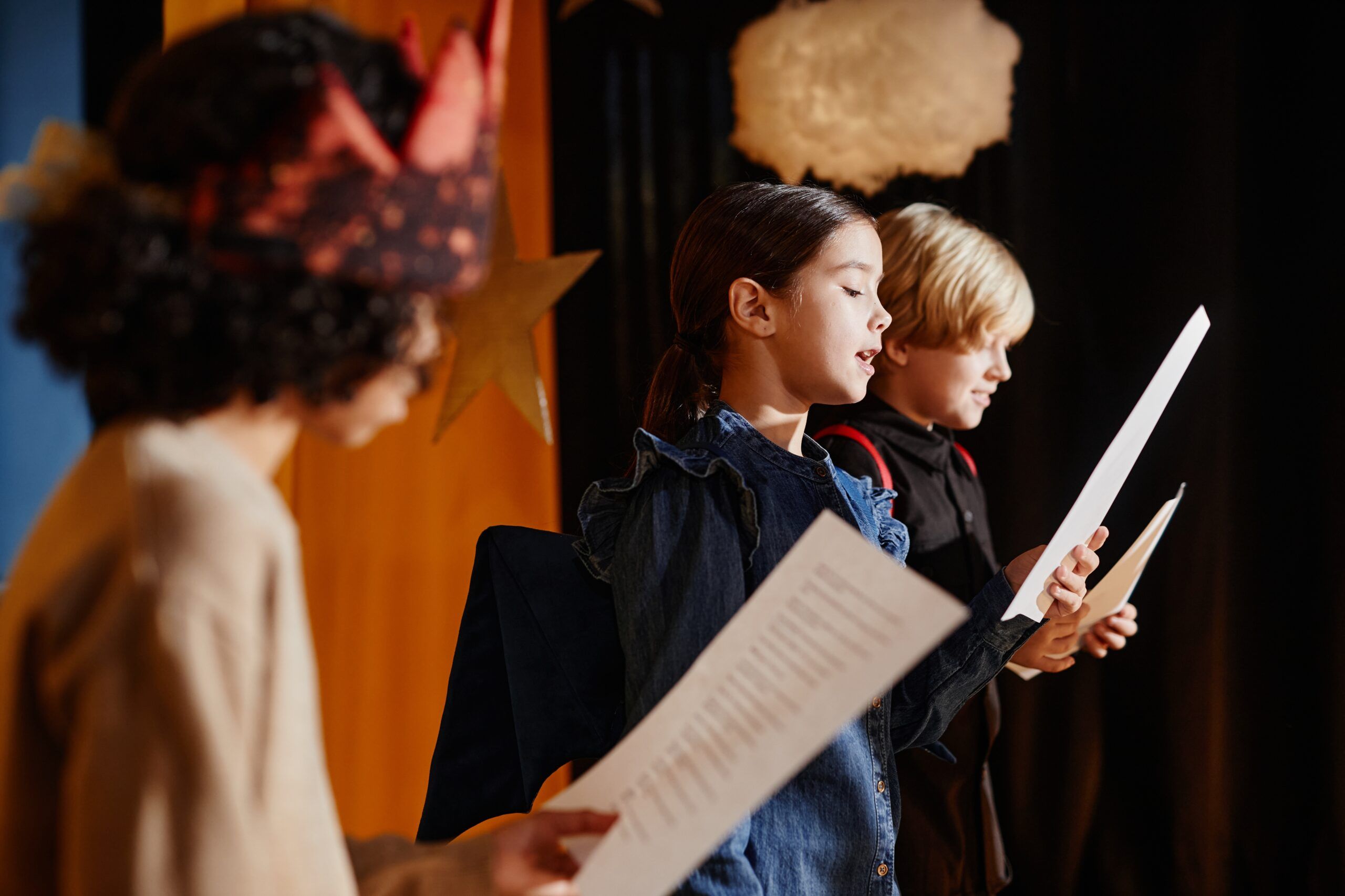 A group of children standing on stage rehearsing for a play.