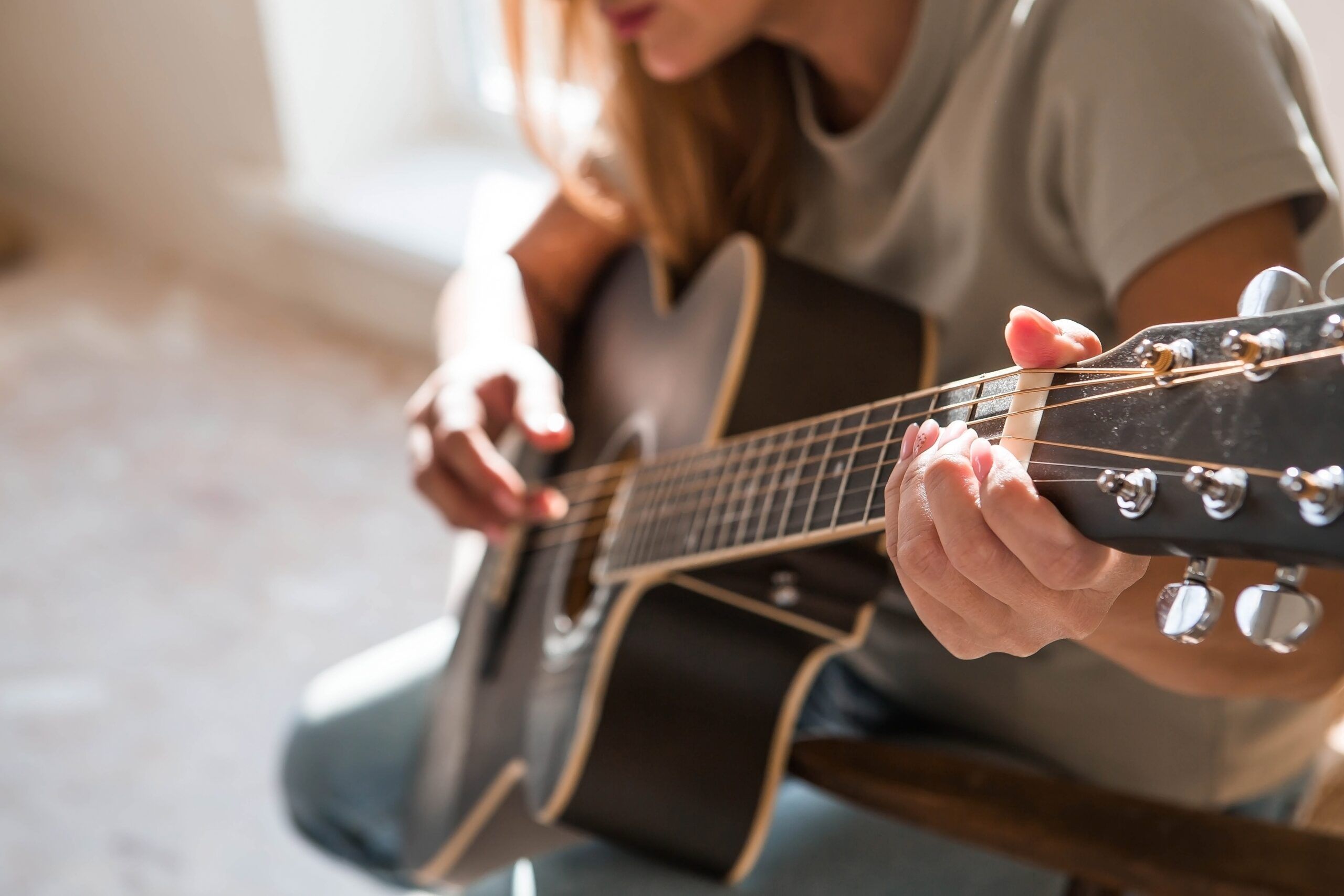 A woman alone playing her guitar.