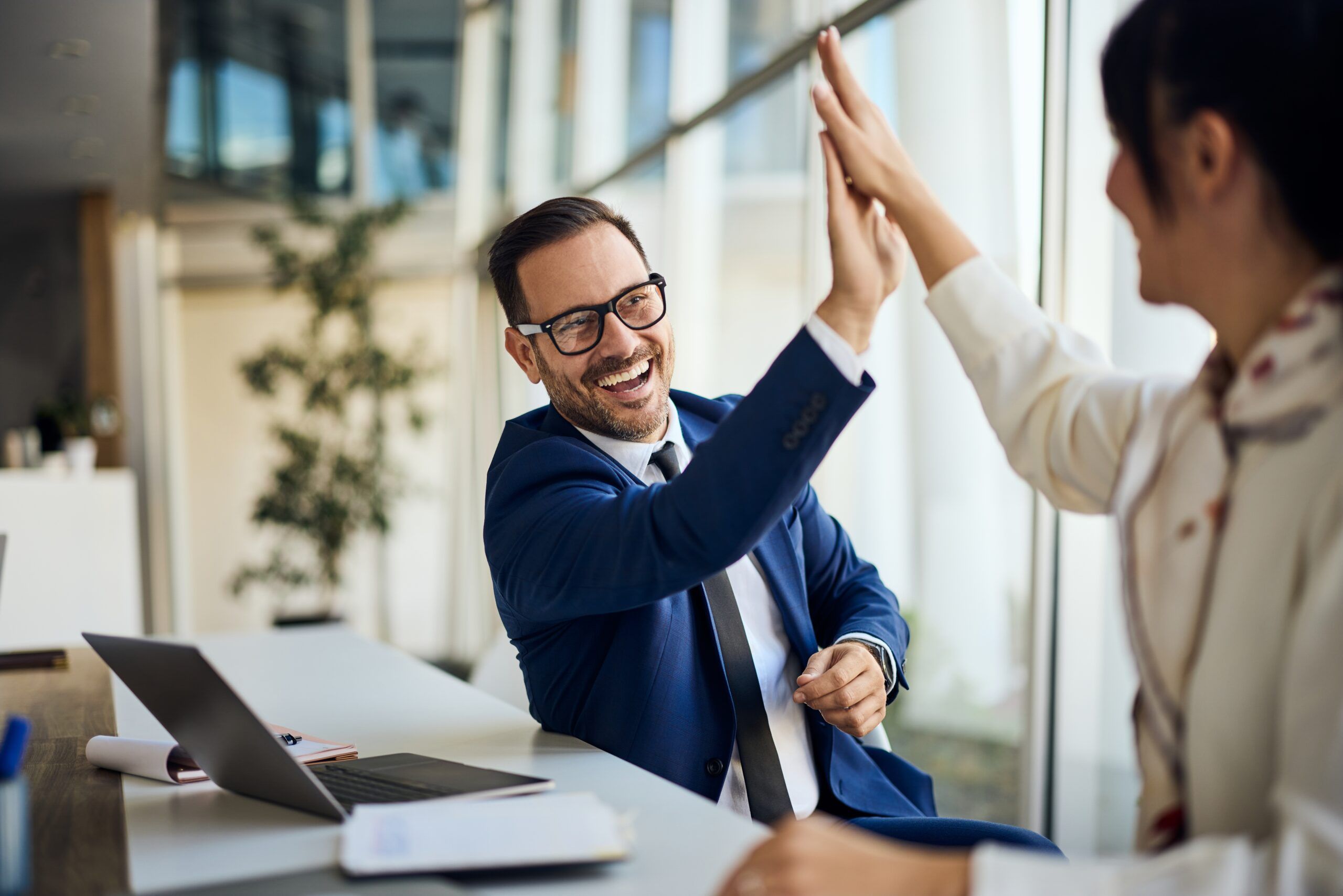Two professionals high-fiving one another after a success.