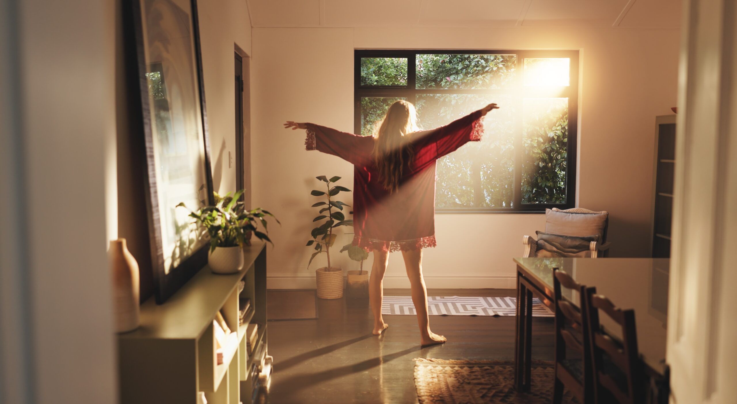 A woman waking up and stretching in the morning sunlight.