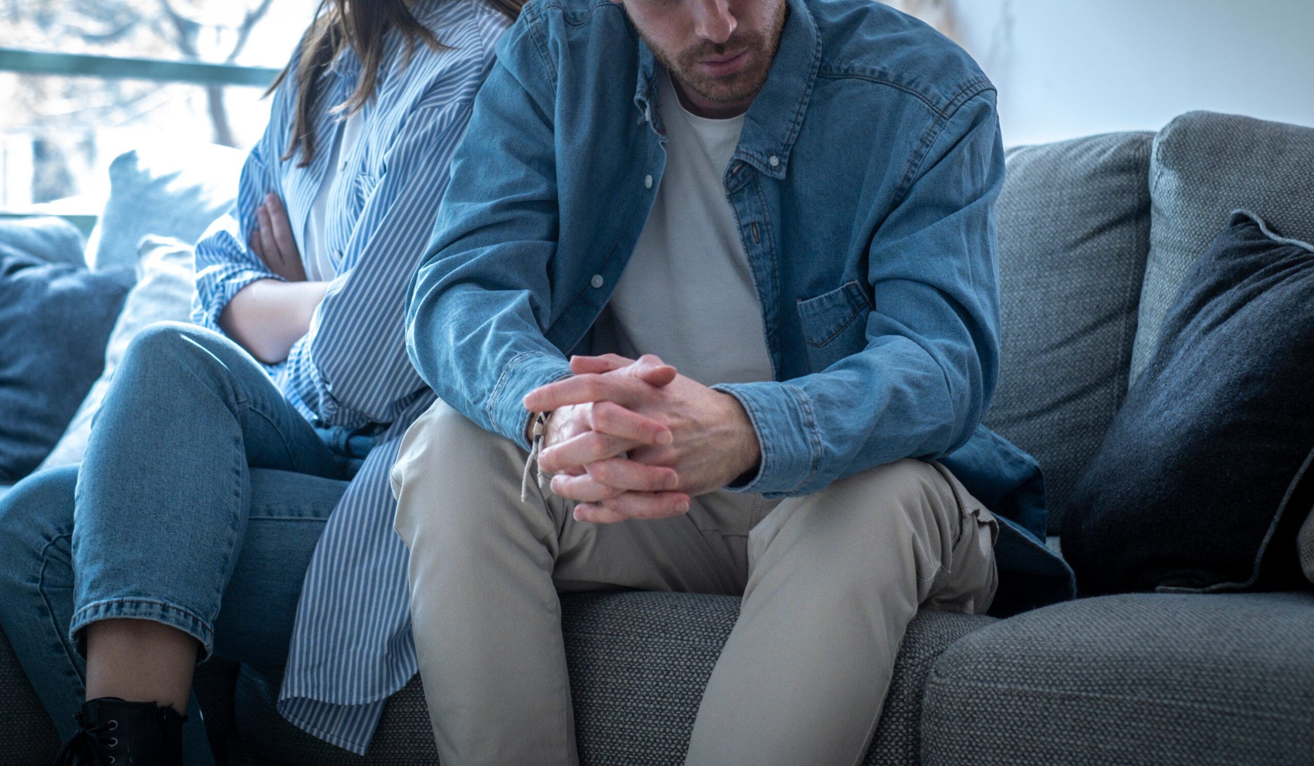 A couple sitting on the sofa unable to confront each other.