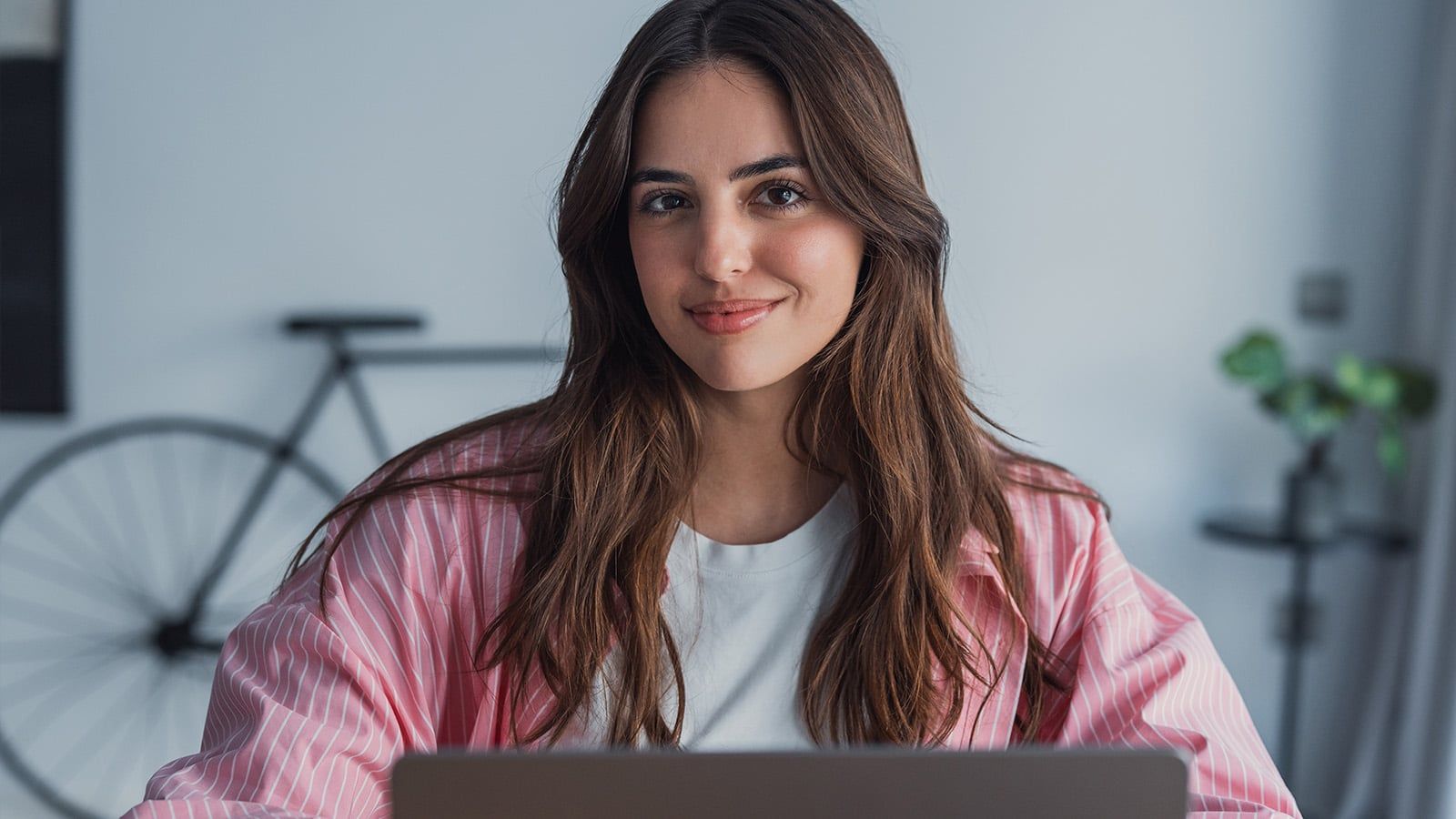 Happy young woman sit at desk look at laptop screen browsing surfing wireless Internet at home, smiling millennial female employee wor