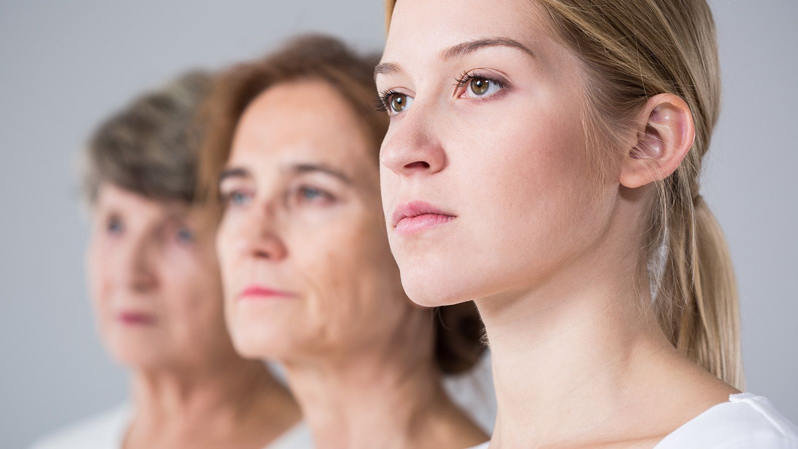 Three women of different ages stand side by side, facing forward. The youngest woman, representing Gen Z, is in sharp focus in the foreground, while the older millennial women behind her are blurred. All have serious expressions.