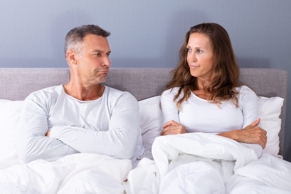 A sad middle age mature couple sitting up in bed
