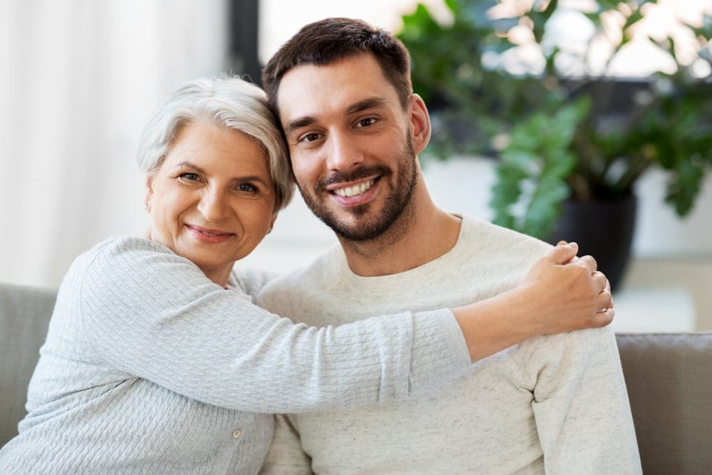 A happy smiling senior mother hugging her son, two generations