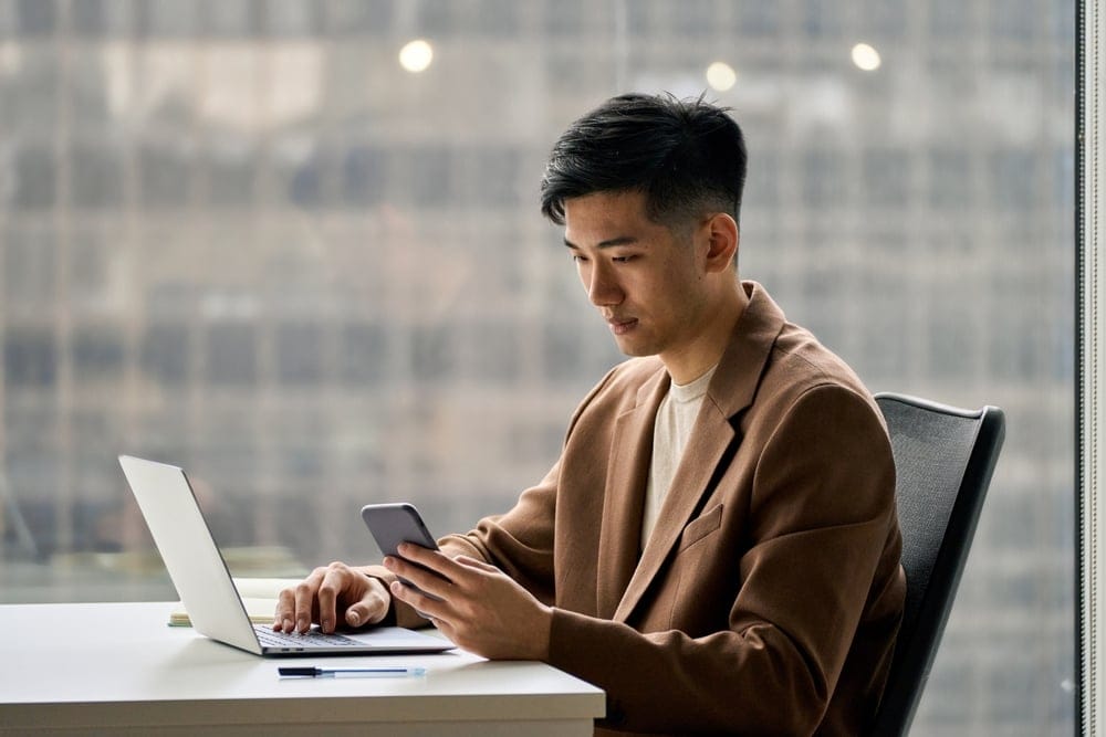 A busy smart and young business man working on his laptop and phone