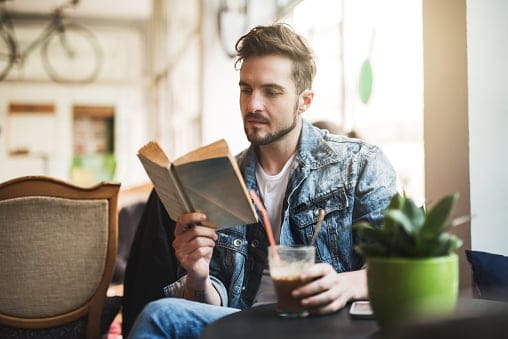 young man reading book with coffee