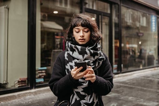 woman texting on city street
