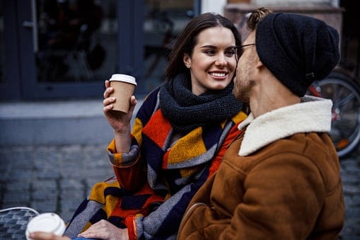 couple having coffee on park bench