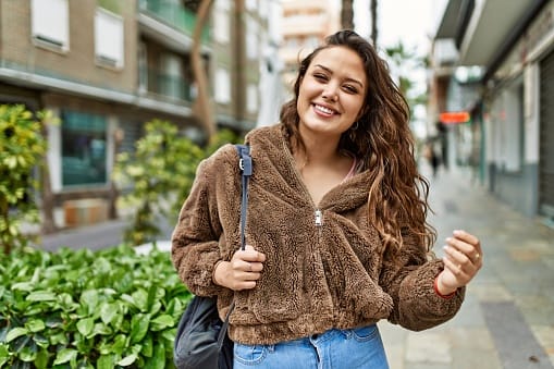 smiling millennial woman on city street