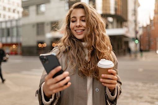 young woman texting with coffee