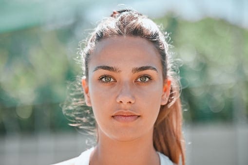 Sports, winner mindset and a portrait woman on outdoor tennis or badminton court before practice game. Health, fitness workout and beauty, headshot of girl with beautiful face and winning motivation.