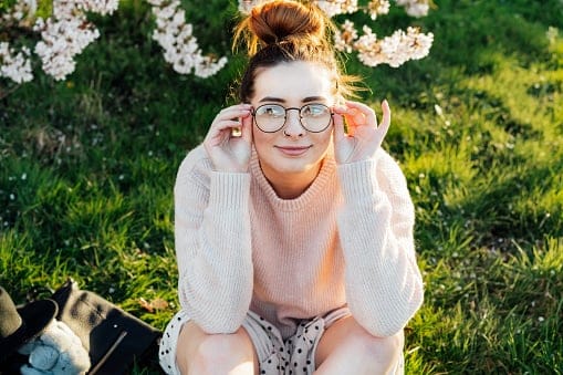 Portrait of young smiling caucasian hipster girl in glasses with pimples, acne on her face. Body positivity and diversity. Teenage skincare problems. Generation Z girl enjoy spring mood