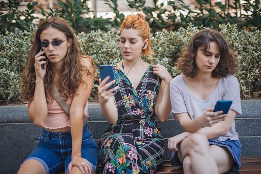 Alienation addiction. Group of girlfriends using smartphones together. Young people addiction to new technology trends. Youth, new generation internet friendship concept. Emotional isolation and depresion