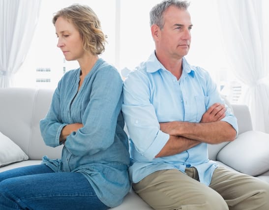 Couple sitting back to back on the sofa.