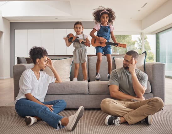 Stress, family and energy with kids playing music on a guitar in the living room at home while giving mom and dad a headache. Mental health, children and tired with a girl and sister causing chaos