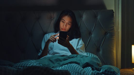 Young Asia girl media addiction on bed can not sleep slide cellphone screen boring disinterest with social content mobile in home at night.