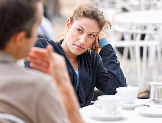 skeptical woman listening to man at cafe