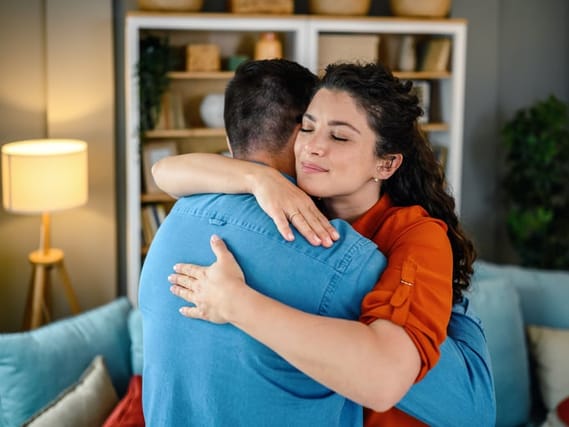Mid adult couple embracing in the living room at home