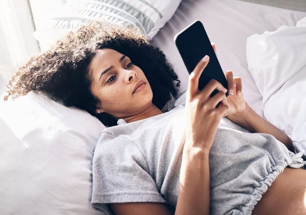 woman laying in bed texting