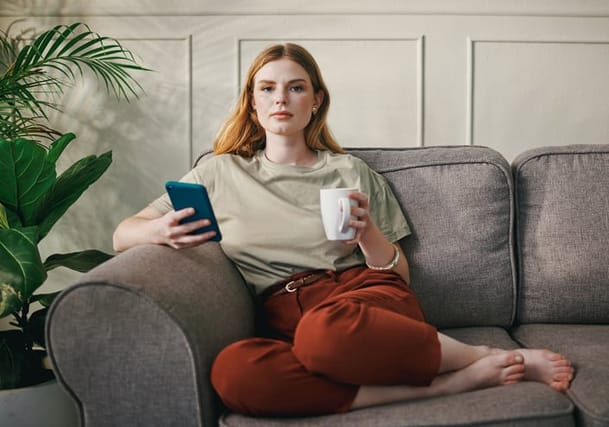 redhead millennial woman with phone on couch