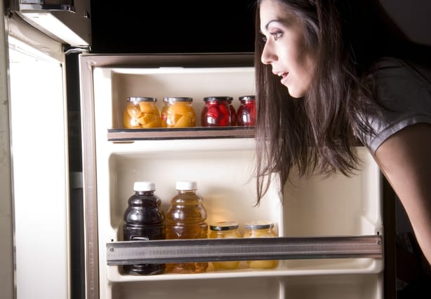 Woman looking inside her refrigerator.