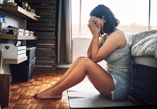 woman covering face in bedroom