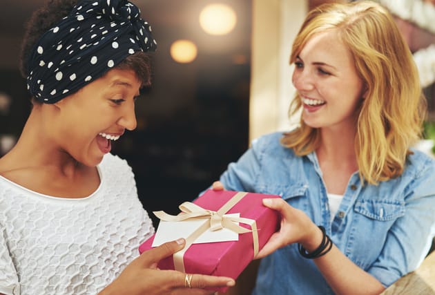 A blond woman giving a gift to her friend