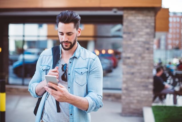 man texting on city street