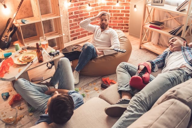 Men sleeping in a messy room.