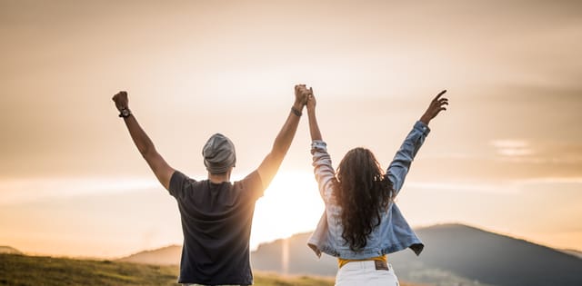 Rear view of young couple celebrating love on a sunset in nature. Road trip adventure.