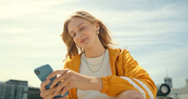 smiling blonde woman texting in sun