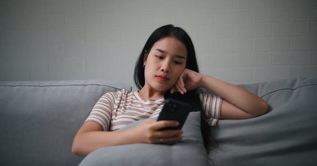 annoyed woman reading text on couch