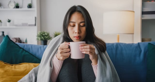 woman sippiing tea on couch