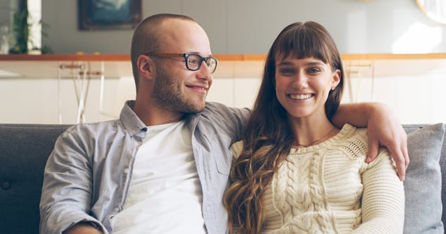Cropped shot of an affectionate young woman smiling while relaxing with her husband in their living room at home