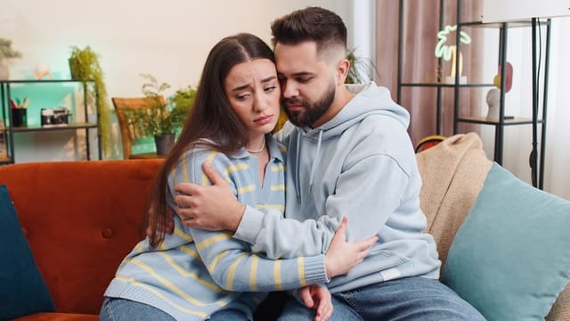 upset couple comforting each other on couch